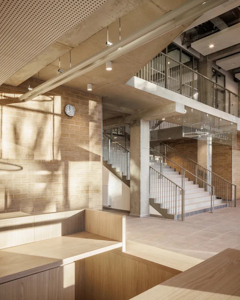 Interior atrium with timber seating and a spiral staircase bathed in morning sunlight