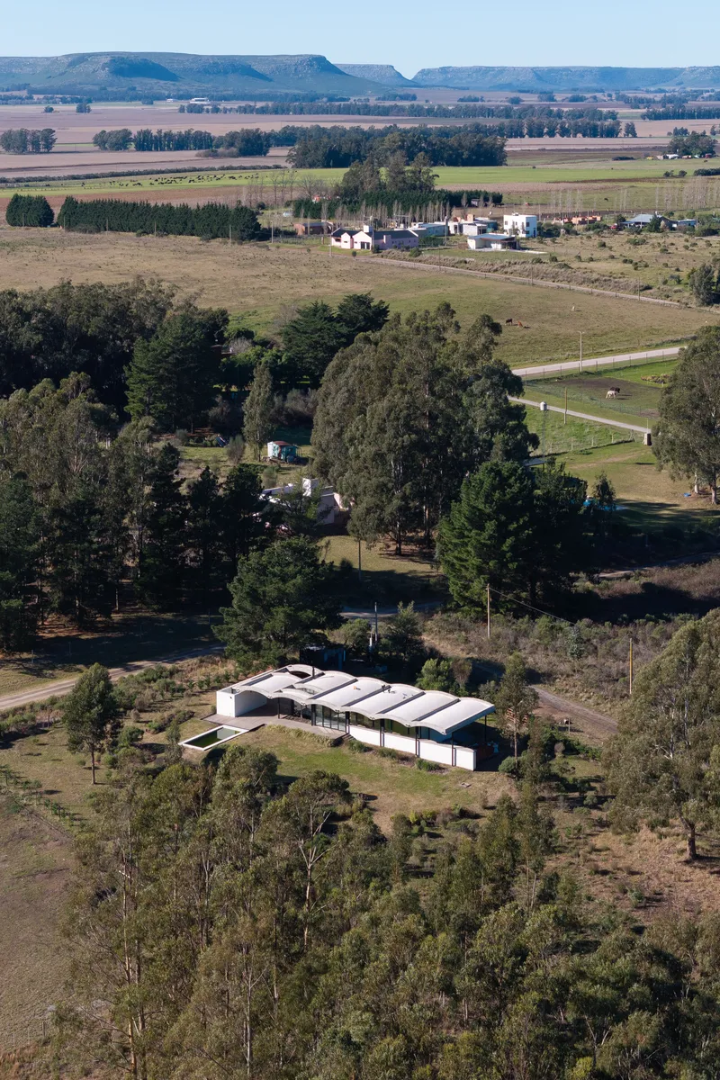 Aerial view of the barrel vaulted roof structure surrounded by scattered trees and farmland
