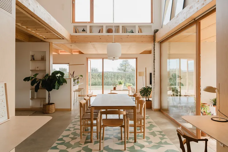 Double-height dining space with exposed timber beams and clerestory windows overlooking landscape