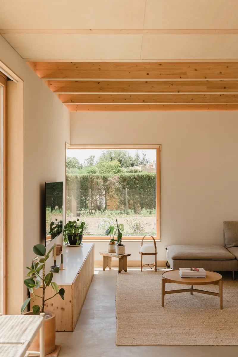 Living room with picture window framing view of hedgerow and planted garden