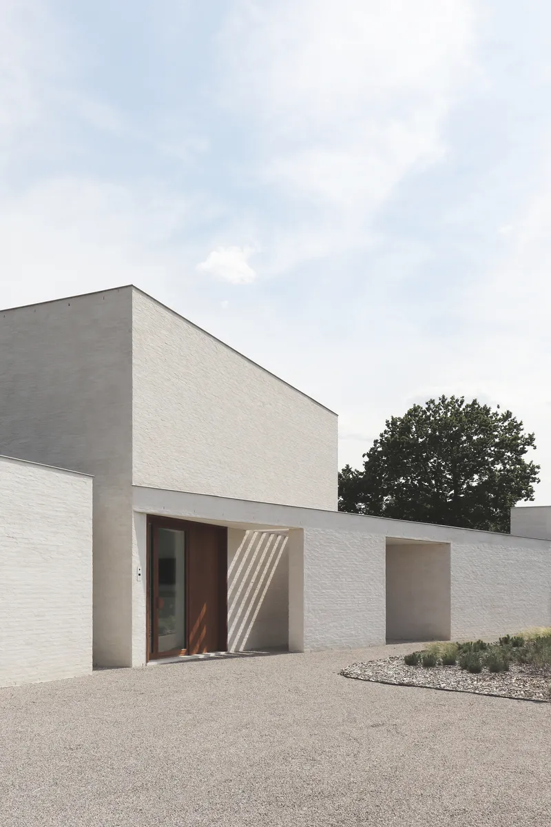 Street-facing elevation showing timber entry door set in white and grey brick walls