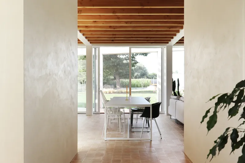 Interior view through dining room with exposed timber beams and terracotta floor tiles