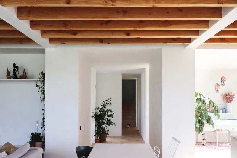 Living space with exposed timber ceiling joists and view through corridor to adjacent room