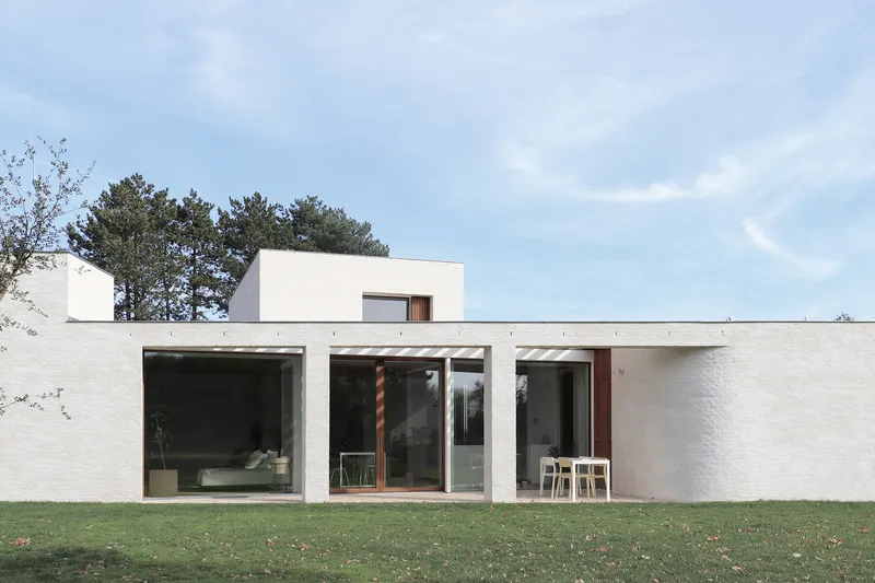 Garden facade with white brick walls and full-height glazed openings onto a lawn