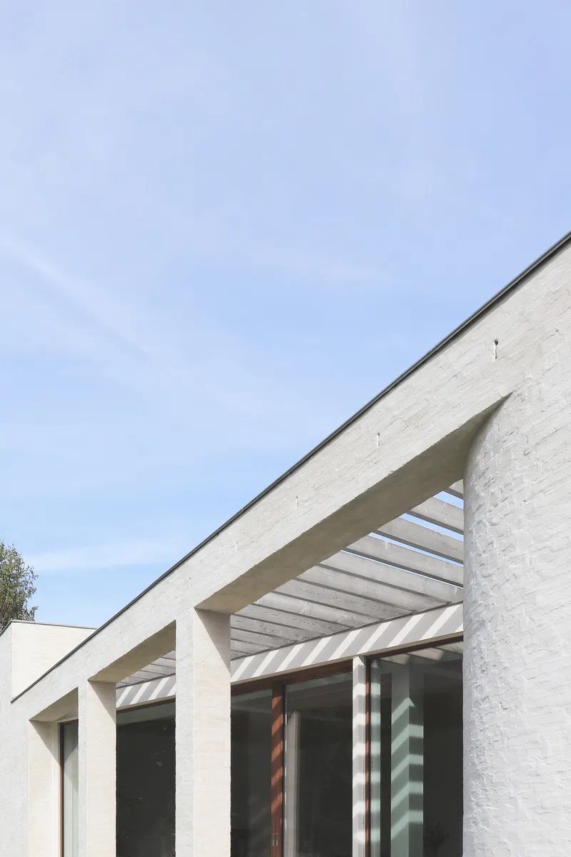 Painted brick facade with concrete slatted canopy under a clear sky