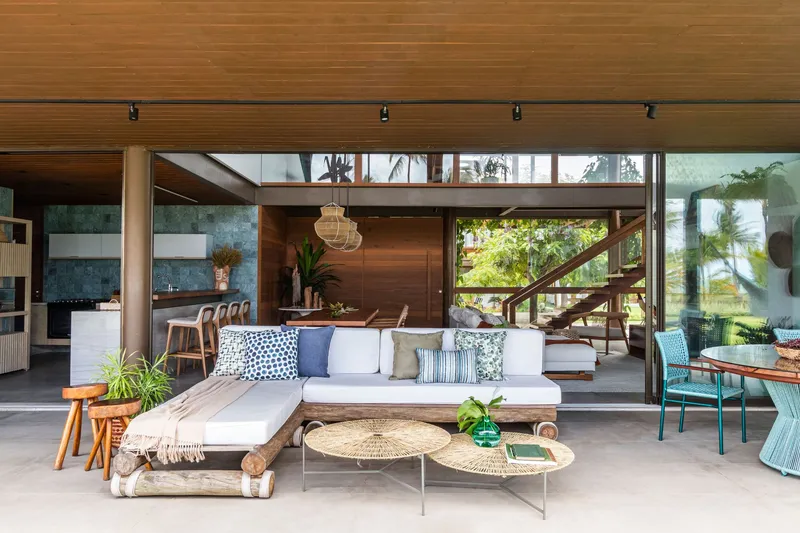 Open-plan living area with timber soffit, glass walls and glimpse of timber staircase beyond seating