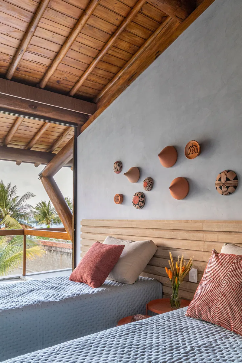 Bedroom wall with terracotta disc artworks above horizontal timber slat headboard and opening to palms