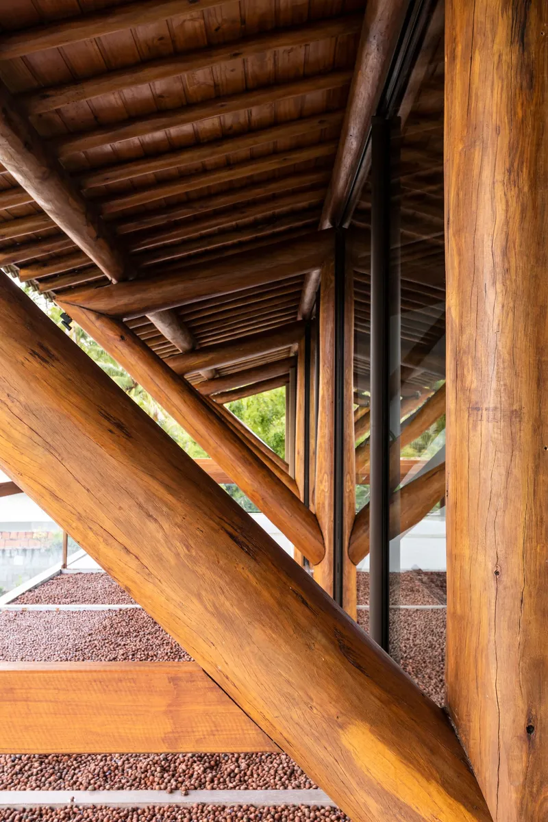 Timber staircase with open risers ascending beneath exposed beams and triangular skylight opening