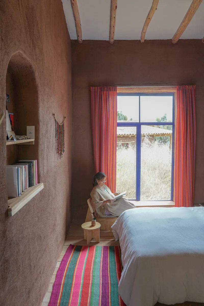 Bedroom nook with person reading by a window framed with striped textile curtains