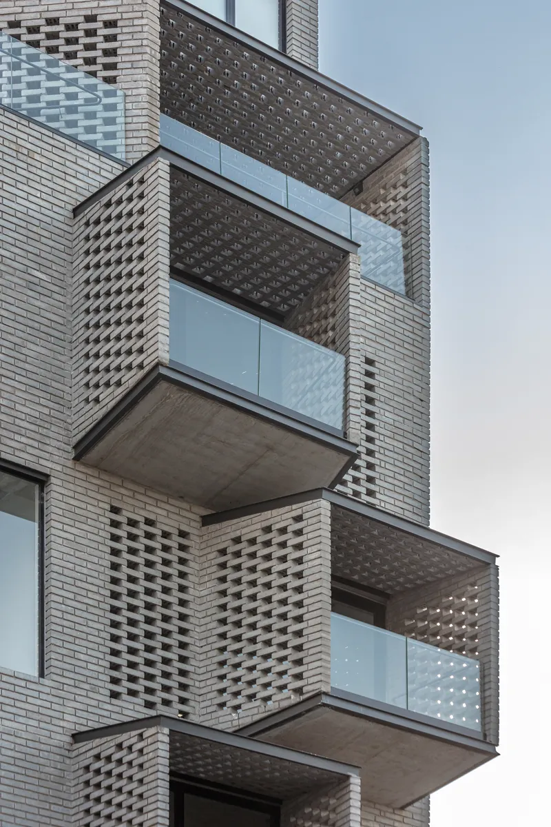 Cantilevered balconies with glass railings and patterned brickwork on residential facade