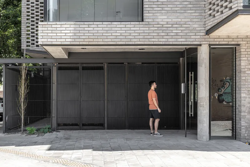 Ground-level entrance with black metal gate and person approaching under brick overhang