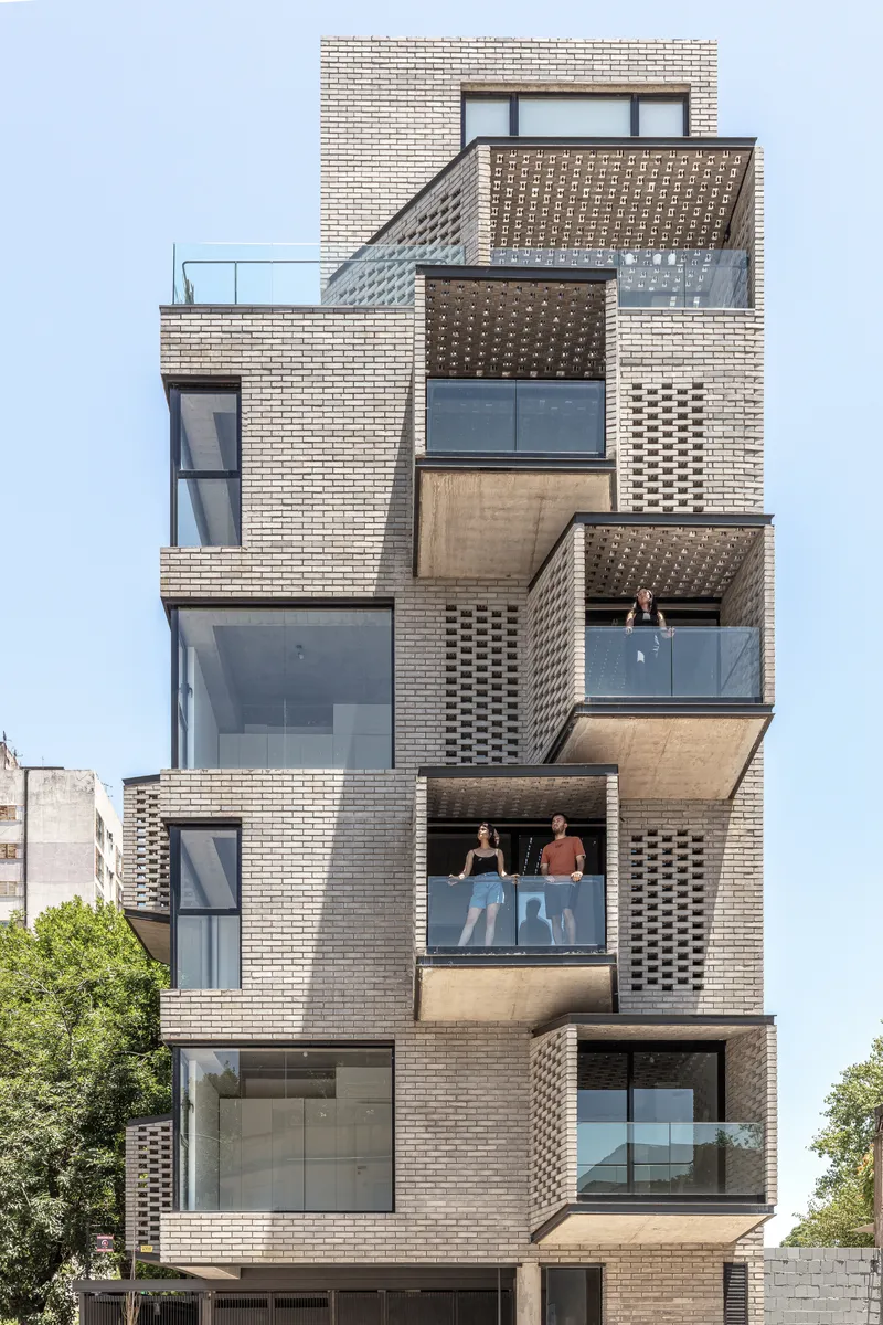 Front elevation showing projecting balconies with perforated brick panels and residents on upper terraces