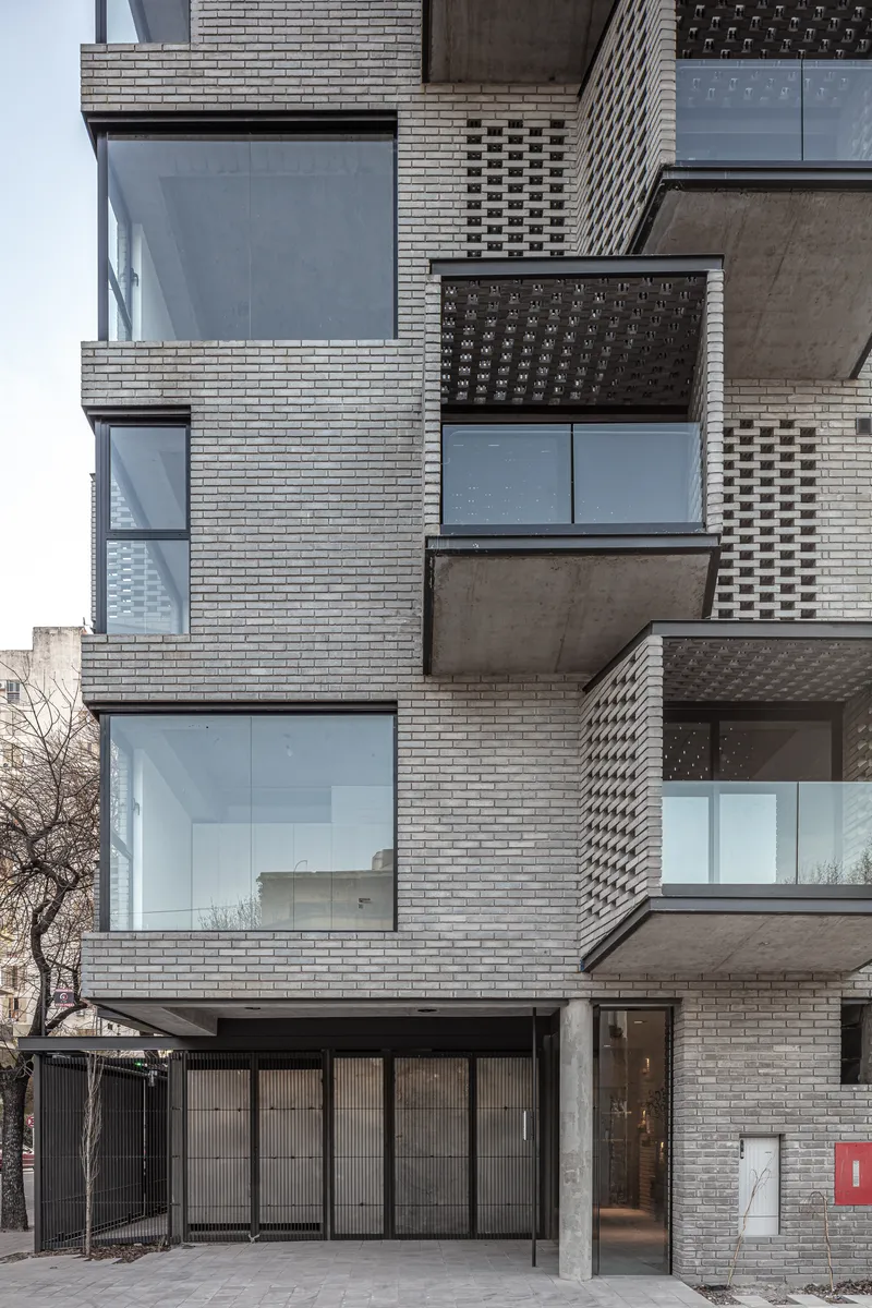 Close-up of the layered brick facade showing alternating perforated screens and glazed openings in daylight