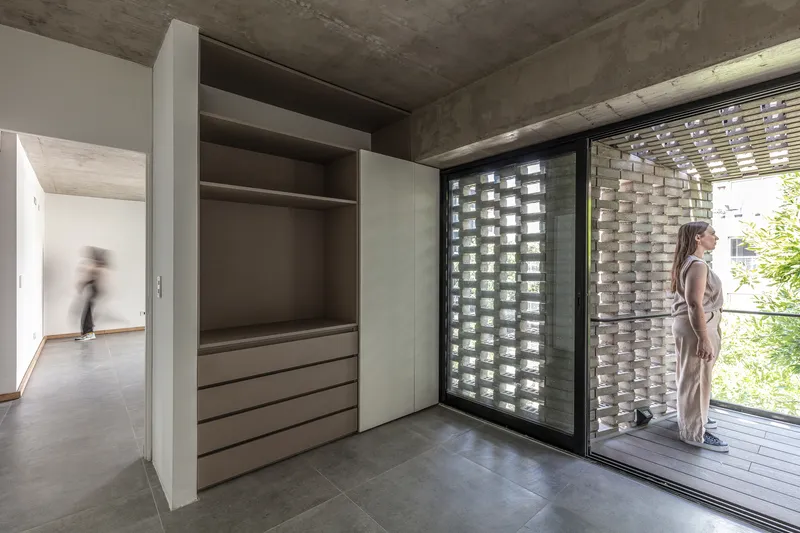 Bedroom with built-in wardrobe opening to a terrace through sliding glass doors and brick screen wall