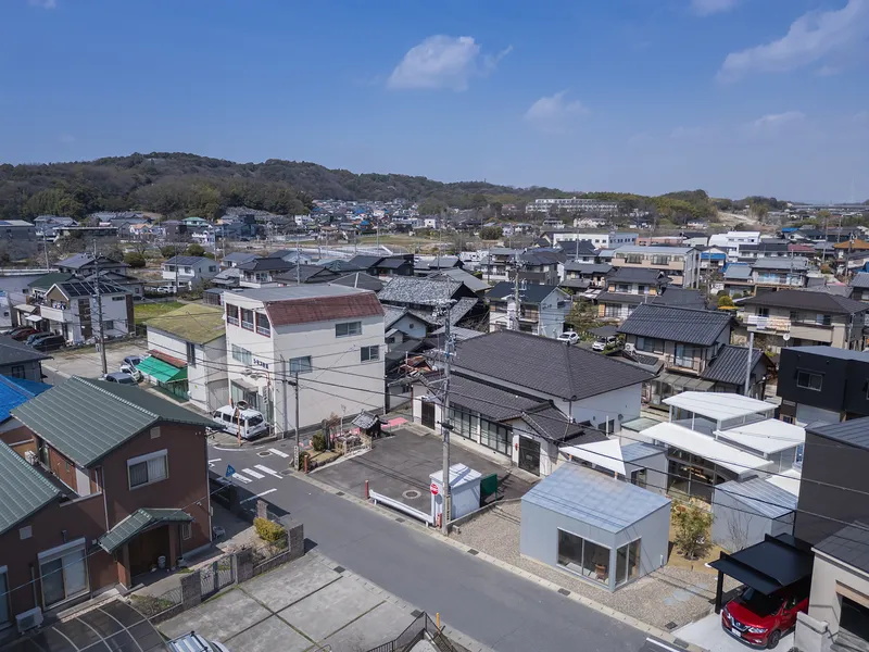 Aerial view of a dense residential neighborhood with varied roof types under blue sky