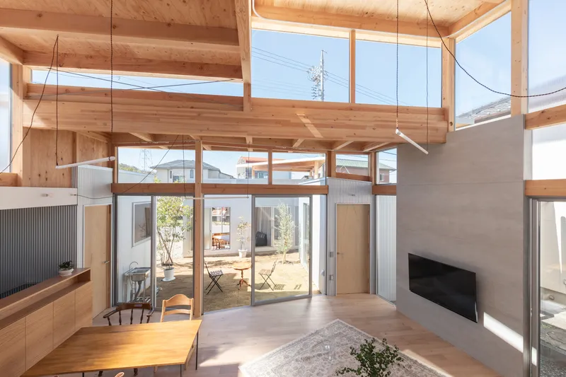 Living space opening onto the courtyard through full-height glazing beneath the layered timber structure