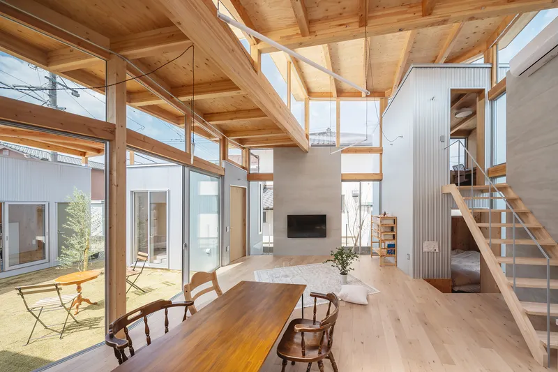 Double-height living space with exposed timber beams and glazed walls overlooking an interior courtyard