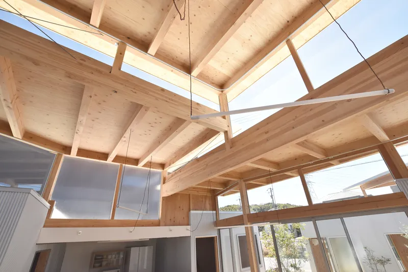 Upward view of the exposed timber ceiling structure with clerestory windows admitting daylight