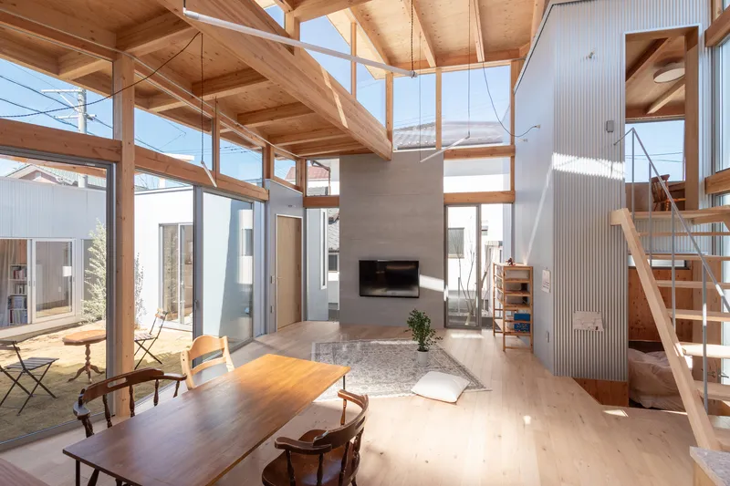 Living room with concrete fireplace wall and suspended light fixture under a timber-framed vaulted ceiling
