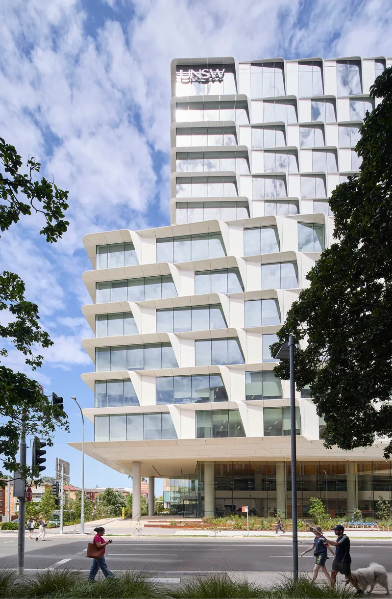 Tower elevation framed by tree branches with pedestrians crossing the street below