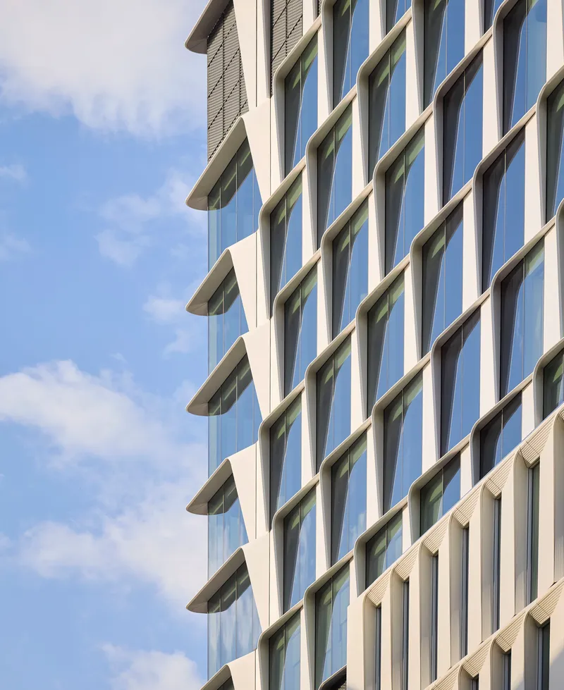Oblique view of the alternating glass and concrete facade against scattered clouds