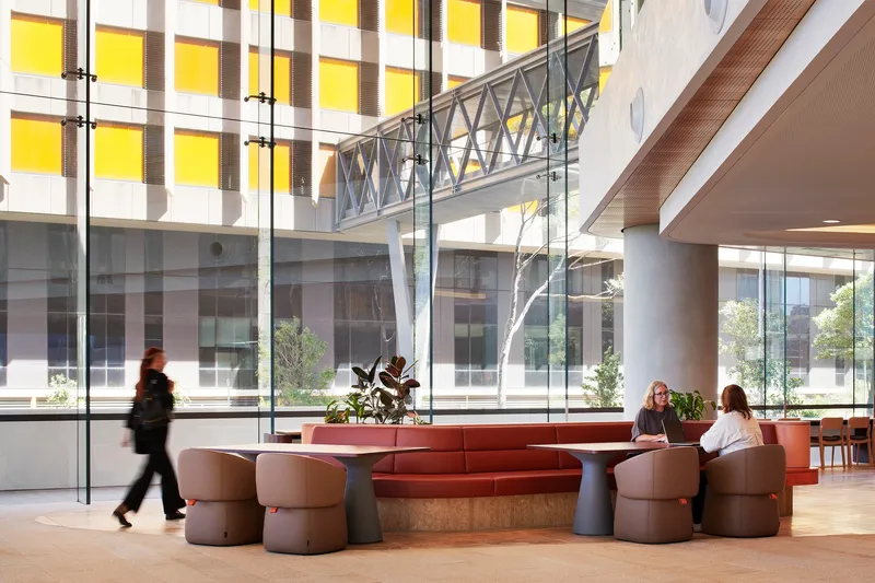 Interior lobby with circular seating pods and a steel bridge spanning overhead