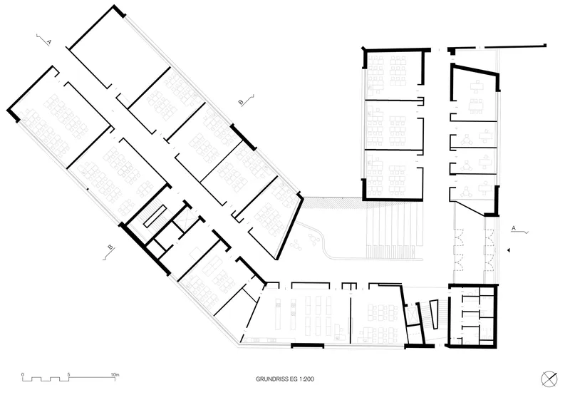 First floor plan drawing showing angled classroom wings with a central stairwell and terrace