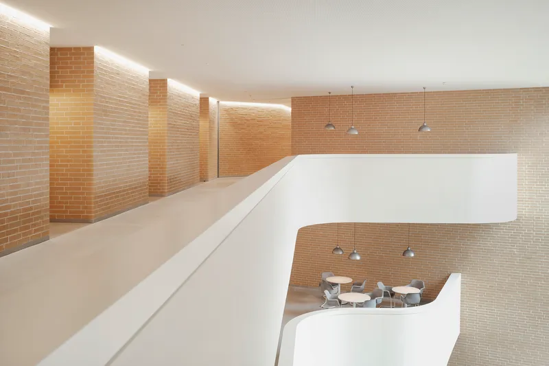 Upper level balcony overlooking a dining area below with yellow brick walls and pendant lights