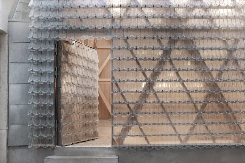 Aerial view of the shingled roof with an open pivoting door revealing the light timber interior