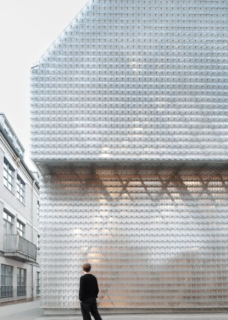 Translucent glass brick facade with recessed opening and a person standing at street level