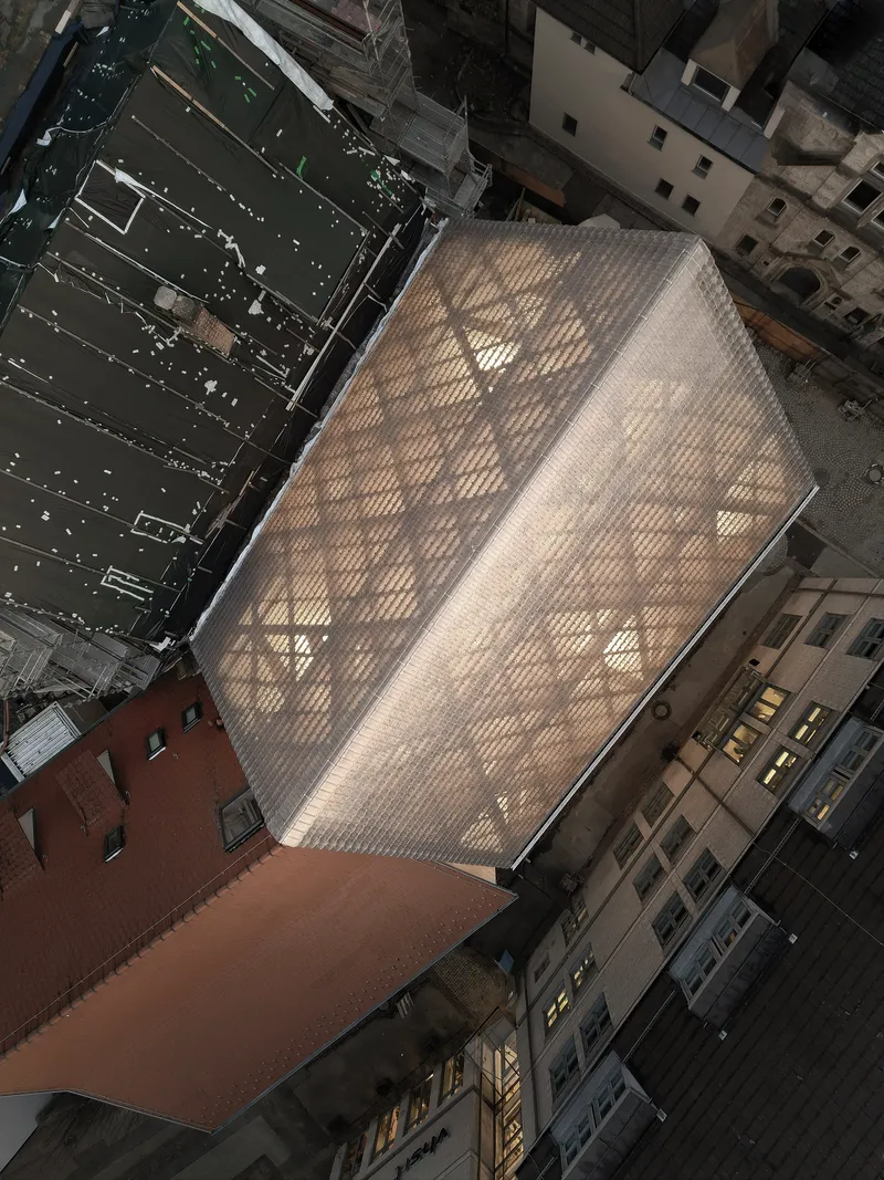Aerial view of the glass brick volume wedged between neighboring buildings in an urban courtyard