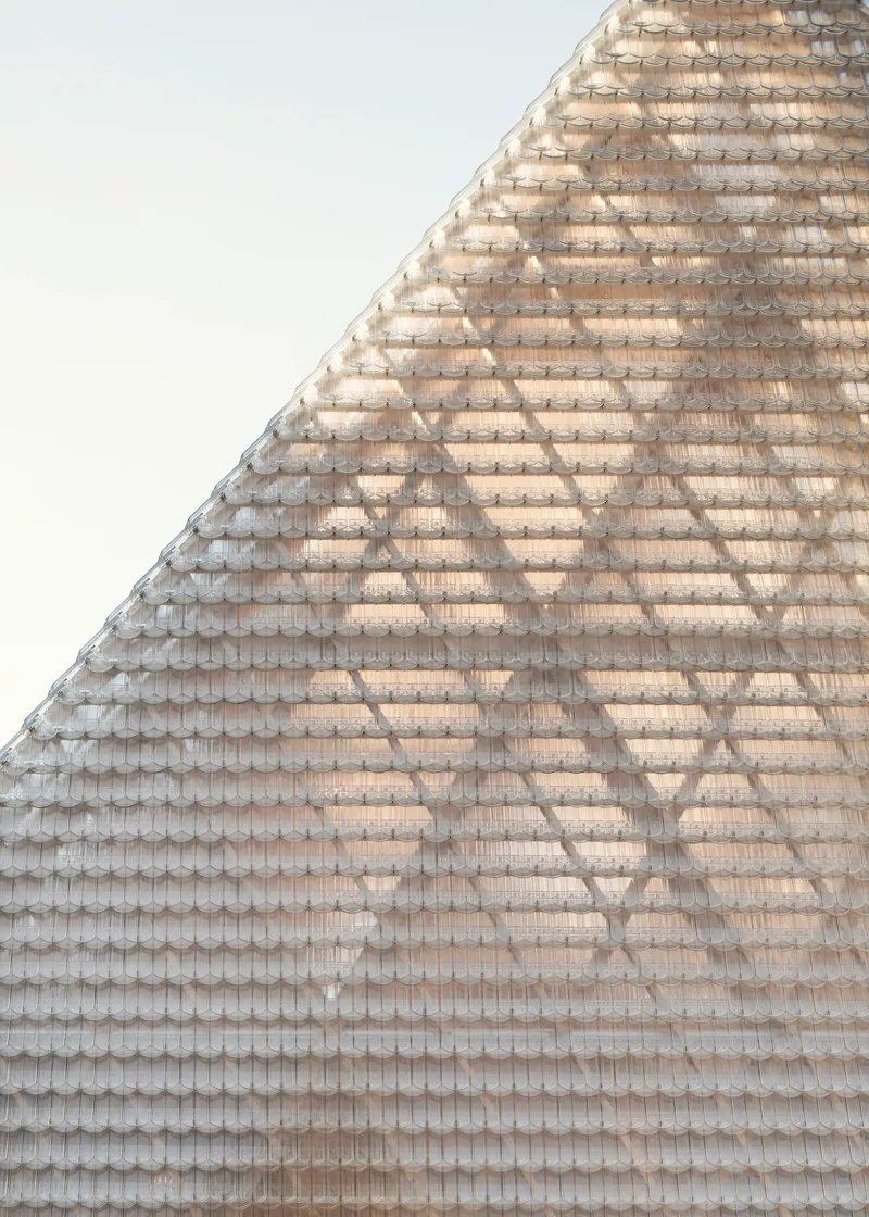 Close-up of the textured glass tile roof surface rising toward a peaked ridge against an overcast sky