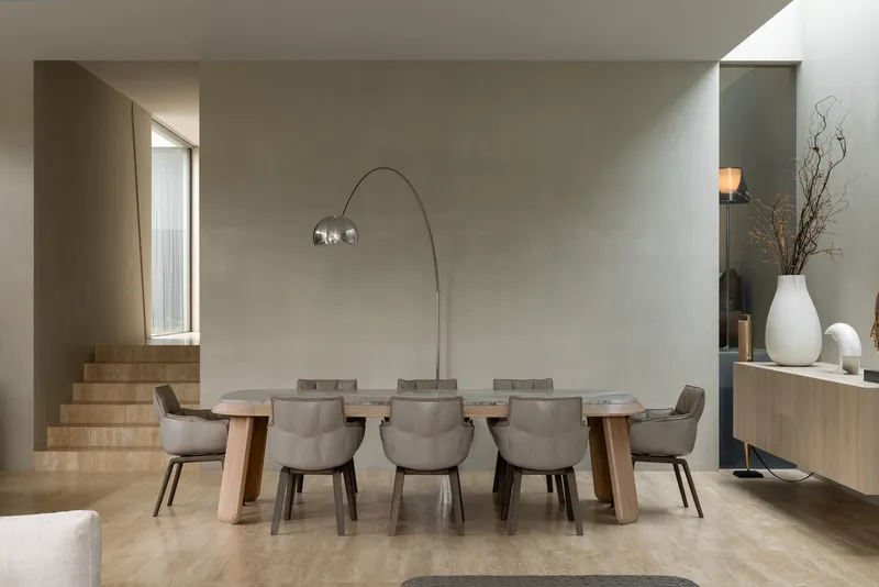 Dining room with stone table and upholstered chairs adjacent to a raised stepped platform