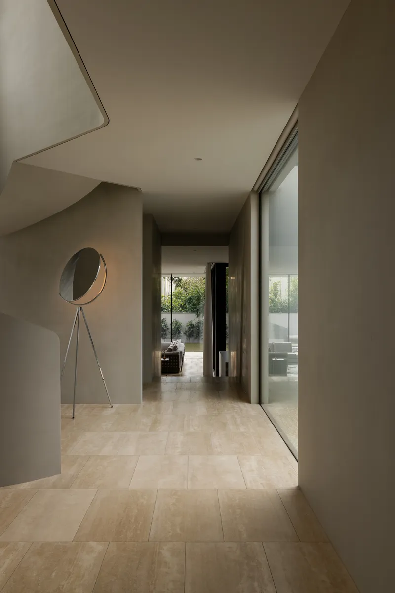 Interior corridor with pale stone floor tiles leading to a glazed courtyard opening