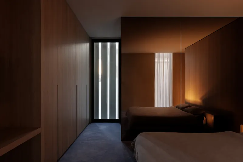 Bedroom with twin beds and vertical strip window lighting the carpeted floor