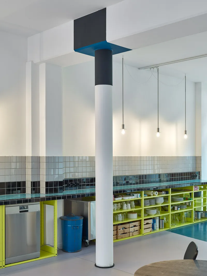 Column detail with blue capital and black crown beside kitchen counter with horizontal tile band