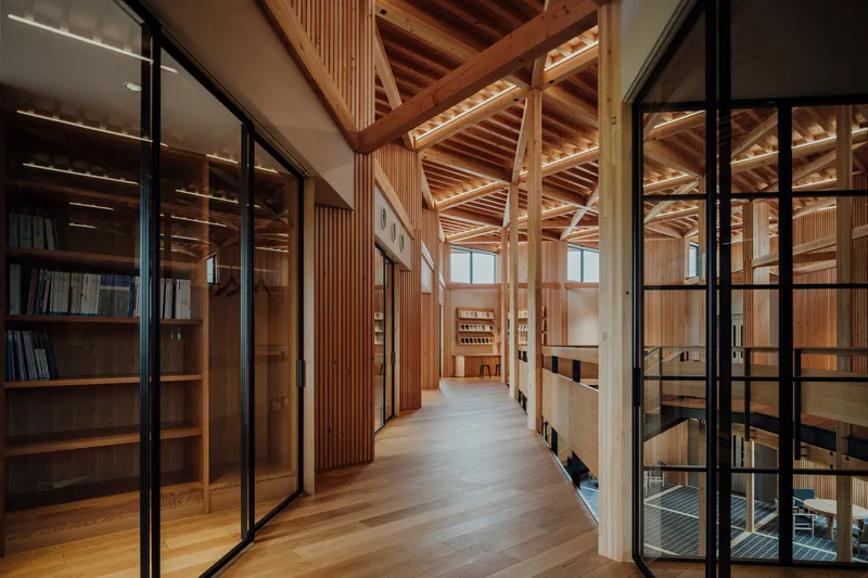 Timber-lined corridor with black steel-framed glass partitions overlooking the lower level
