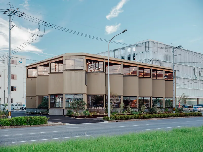 Street view of the corrugated metal facade with sawtooth roof under overhead power lines