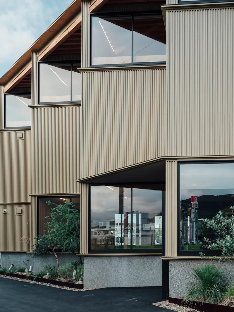 Facade detail of staggered windows with reflections in the ribbed metal cladding at twilight