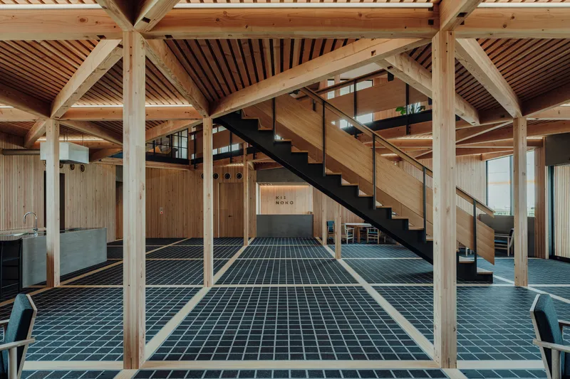 Open interior showing exposed timber frame with blue grid floor tiles and steel staircase to mezzanine