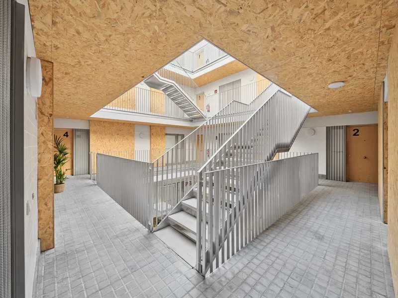 Diagonal view of central staircase with vertical metal slats beneath an angular skylight