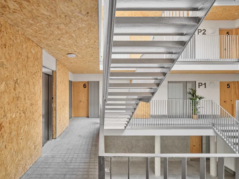 Corridor view along an upper floor with open stair treads and numbered doorways