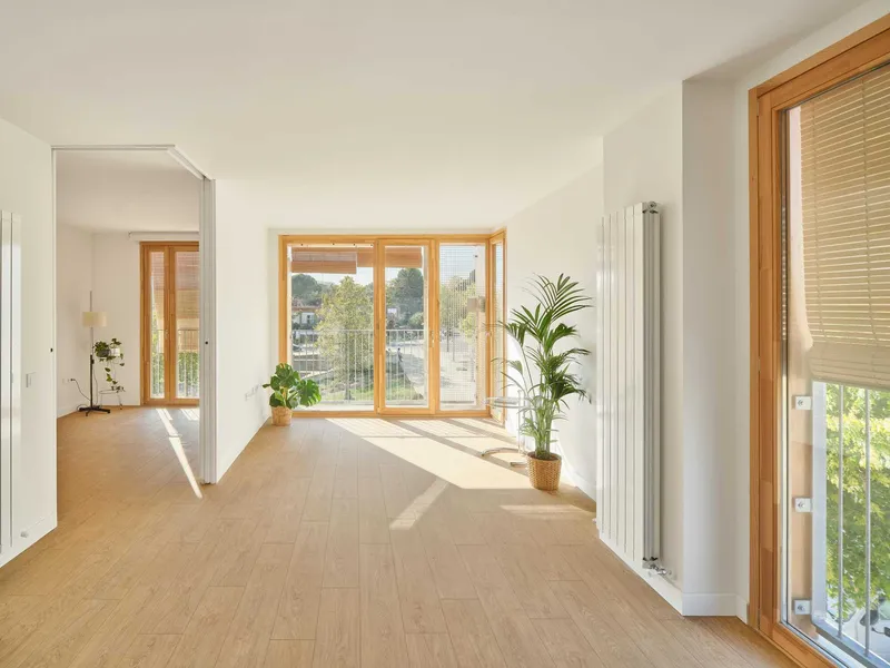Light-filled living space with timber-framed glazed doors and potted plants on pale wood flooring