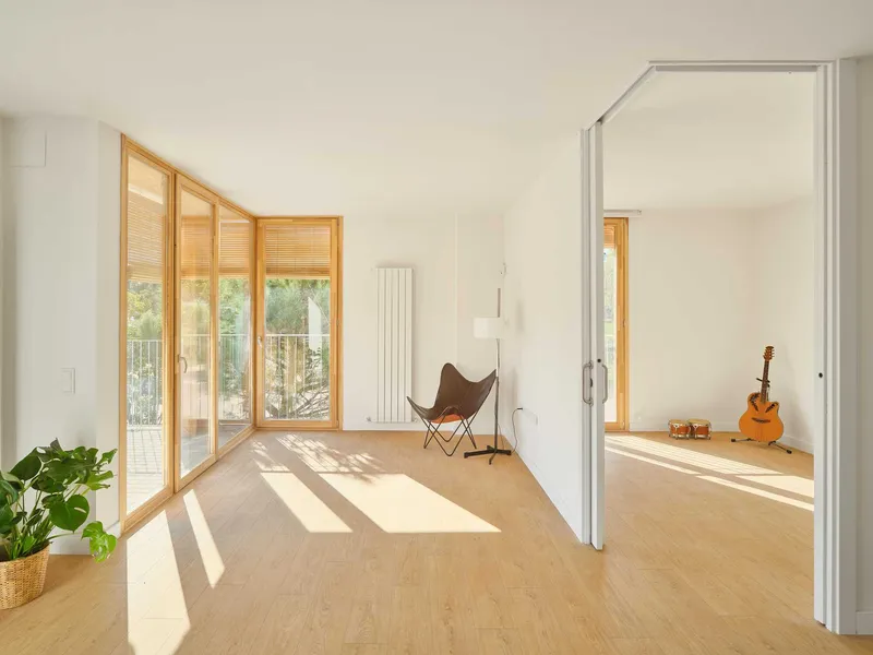 Interior room with angled sunlight crossing cork flooring and a butterfly chair near the window