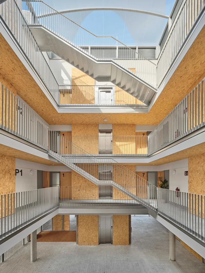 Four-story atrium courtyard with zigzagging stairs and oriented strand board panels wrapping the circulation galleries