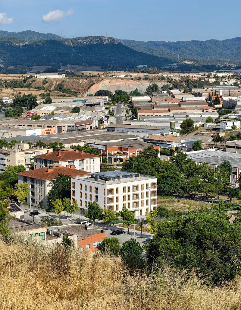 Elevated view of a white residential block set within an industrial valley with distant mountains