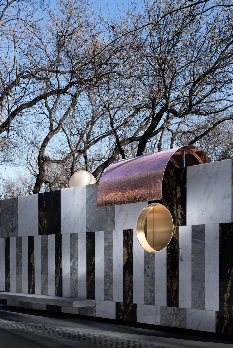 Close view of copper barrel vault and brass disc penetrating alternating light and dark stone panels