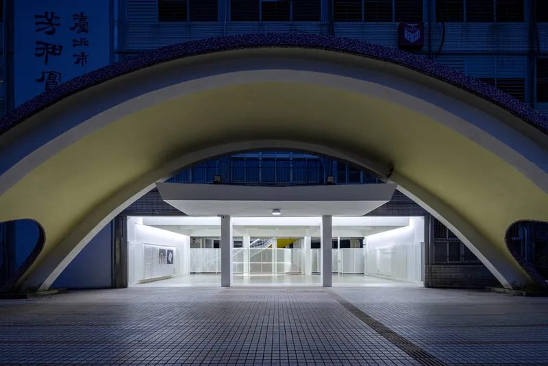 Arched entrance with glowing white interior set beneath a curved vault at twilight