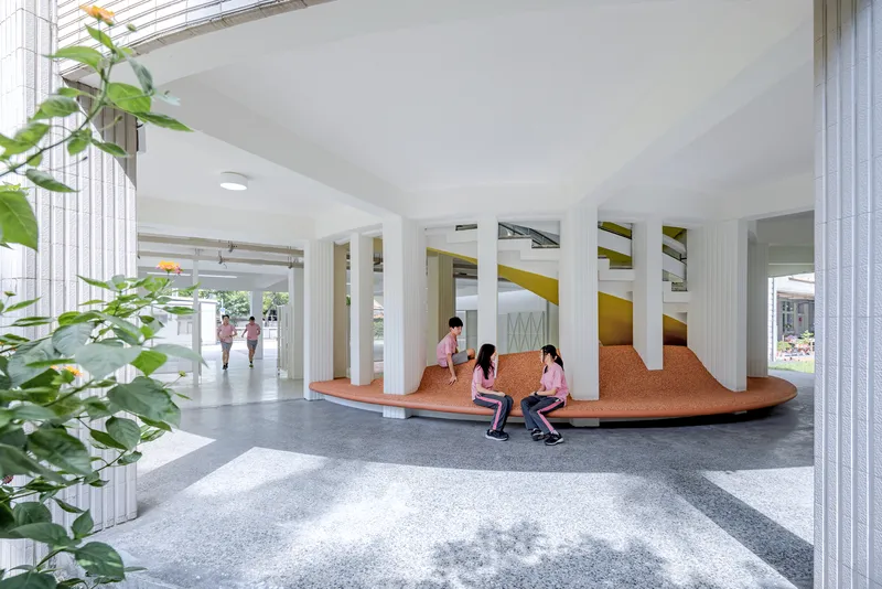 Interior communal space with a cork-clad curved seating platform ringed by white fluted columns