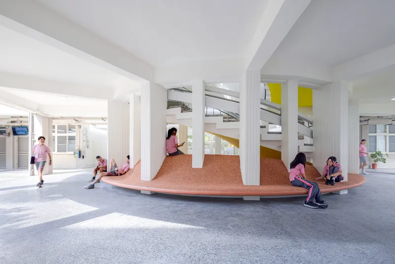 Students gathered on the terraced cork seating platform beneath white columns and exposed ductwork